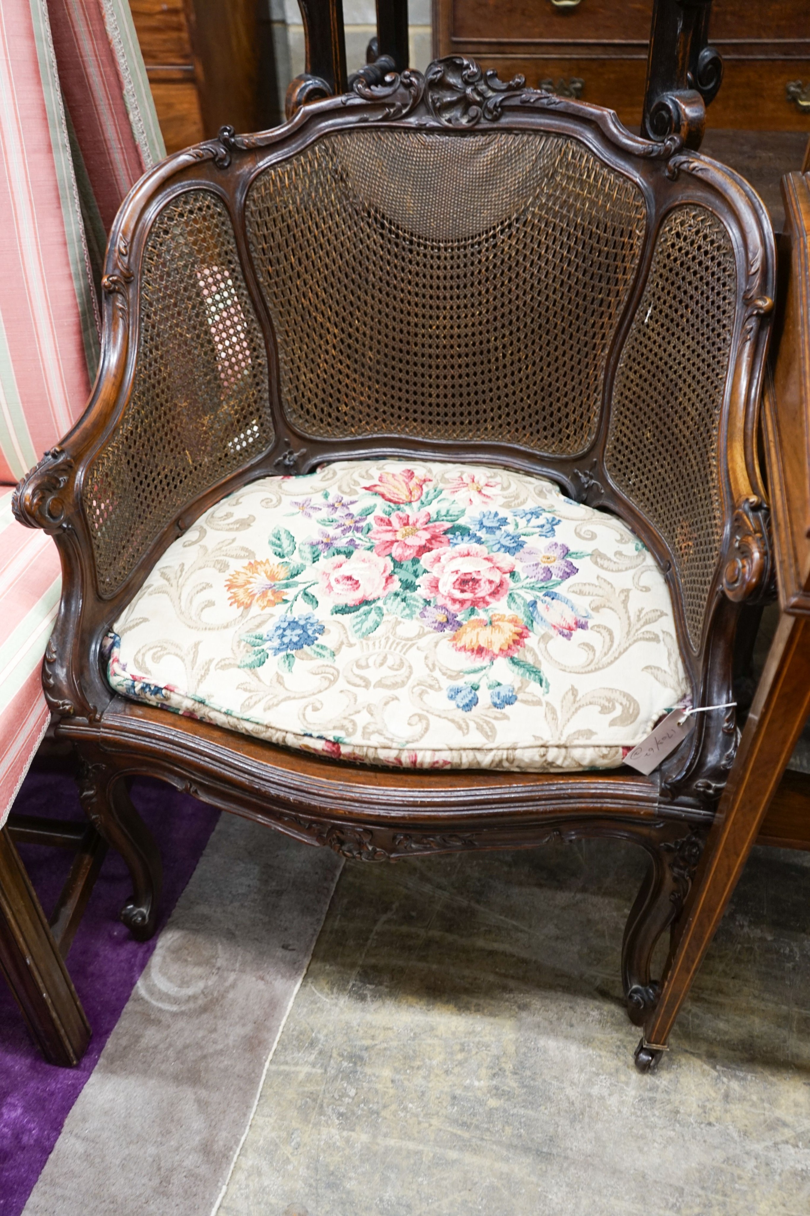 A French style carved walnut frame bergere with caned panels on cabriole legs, length 70cm, depth 52cm, height 86cm together with a Carolean style caned stool